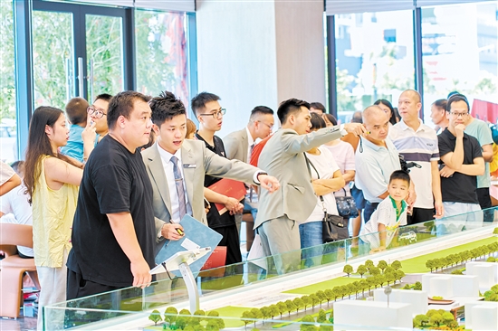 在駿景灣·品悅，銷(xiāo)售人員忙著為客戶介紹樓盤(pán)情況。