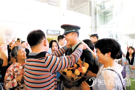 身著軍裝的返鄉(xiāng)退役士兵逐一出站，迎接他們的是鮮花與擁抱。