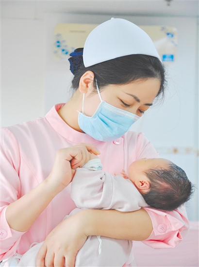 這是一雙托起生命的手。江門市中心醫(yī)院愛嬰?yún)^(qū)主管護(hù)師湯玲玲正在安撫哭鬧的寶寶。她一手環(huán)住襁褓，一手牽起寶寶的小手，動(dòng)作舒緩而溫柔。在這里，生命的啼哭與溫柔的守護(hù)相遇，匯聚成世間至暖的力量。（林錦棠