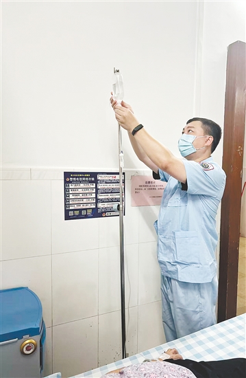 吳益浩核對(duì)藥液、為患者調(diào)整輸液流速。