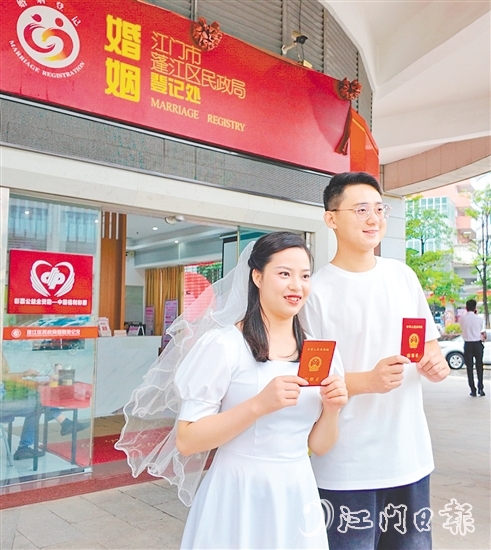 一對新人在蓬江區(qū)民政局婚姻登記處門口合影留念。