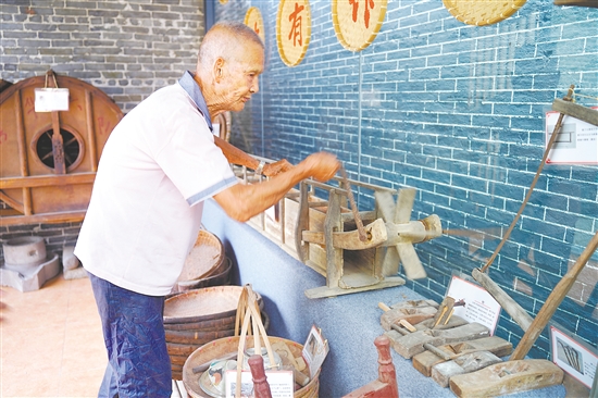 新華村打造農(nóng)耕文化展館，留住鄉(xiāng)村記憶。圖為村中老人向記者介紹農(nóng)具。