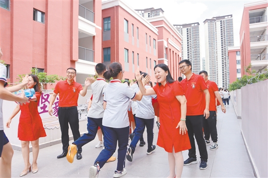 蓬江區(qū)紫茶中學(xué)的領(lǐng)導(dǎo)和老師們與考生們擊掌，為他們加油、鼓勁。