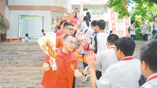 在景賢學(xué)校考點(diǎn)，老師們手持向日葵和小紅旗為考生加油。