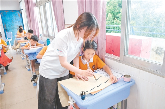 社會實踐隊隊員指導(dǎo)學(xué)生練習(xí)硬筆、軟筆書法。
