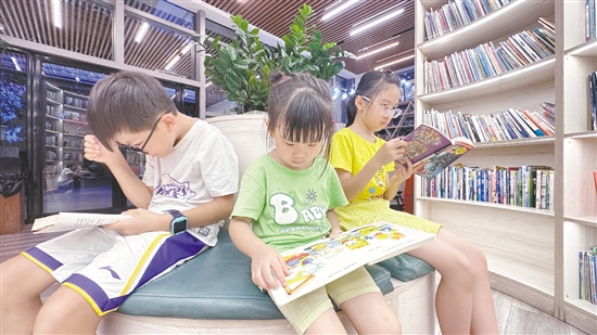 低年級(jí)學(xué)生圍坐在書(shū)架旁閱讀繪本。