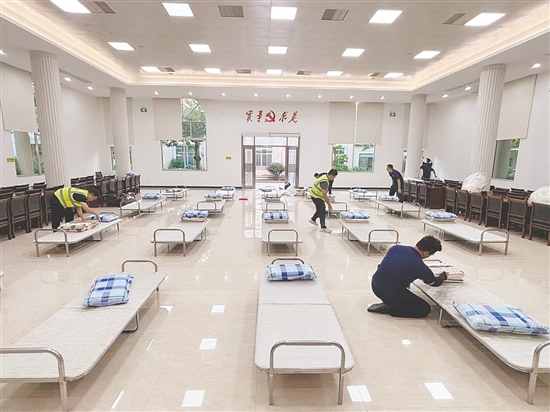 工作人員正在臨時(shí)庇護(hù)場(chǎng)所鋪設(shè)床位。